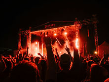 A happy crowd at an outdoor rock concert raising their hands in the air towards the stage