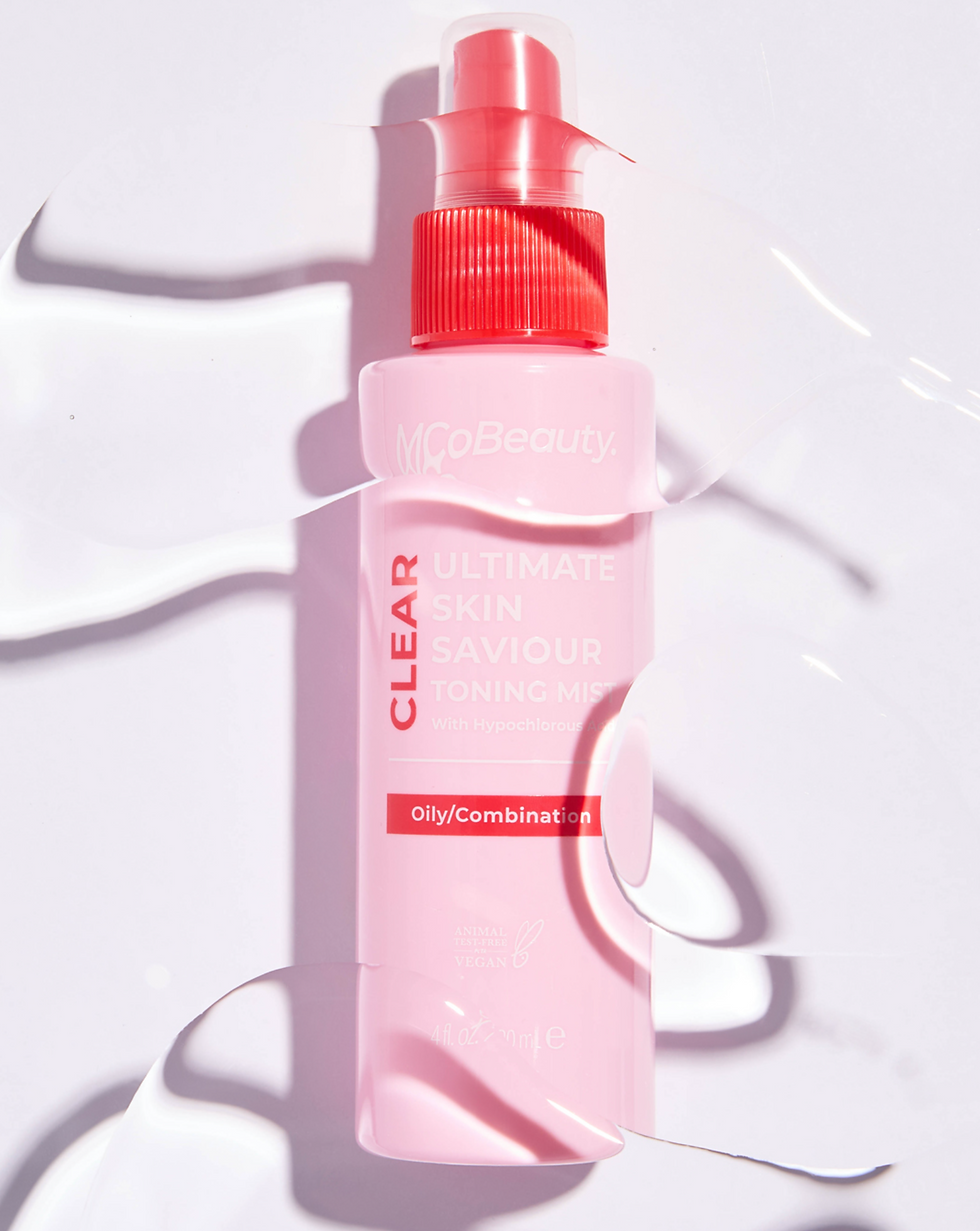 Pink toner bottle with red nozzle labeled "CLEAR ULTIMATE SKIN SAVIOUR TONING MIST." Clear liquid drops around on a white background.