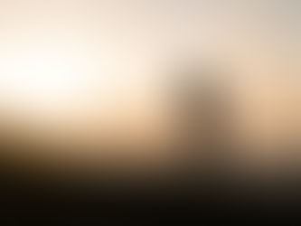 Silhouette of a woman stretching her arms wide on the seashore as the sun rises behind her