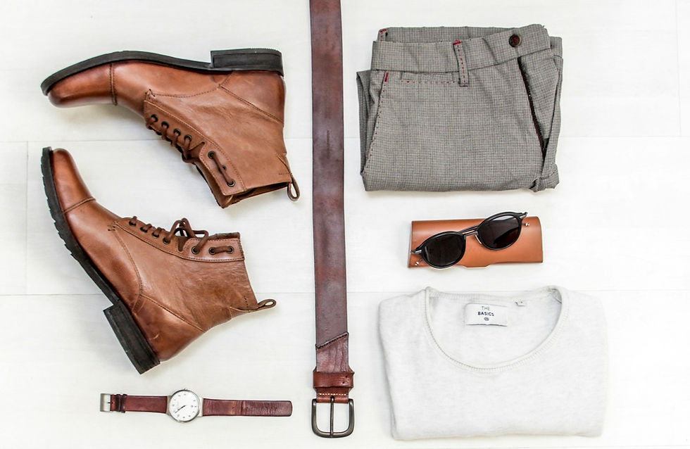 Brown boots, watch, belt, and sunglasses laid out with gray plaid pants and a white sweater on a white surface, creating a stylish ensemble.