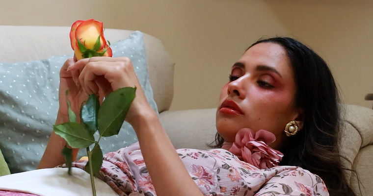 Una mujer acostada en un sofá sosteniendo una rosa.