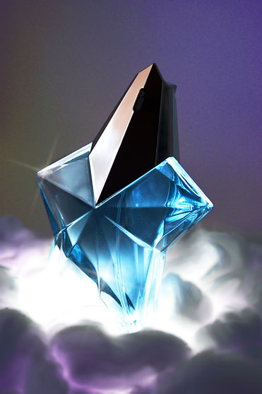 Fotografía de un perfume azul brillante con forma de estrella sobre unas nubes moradas