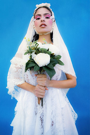 Foto editorial de una chica con un velo y unas flores blancas.