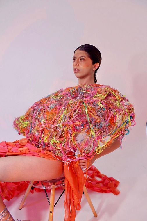 Una mujer sentada en una silla cubierta de hilos coloridos..