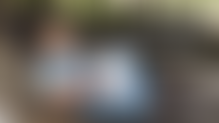 Woman in floral shirt and glasses writing in notebook on wicker chair. Background of wooden deck and canoe. Text: Giving Up vs Stepping Back.