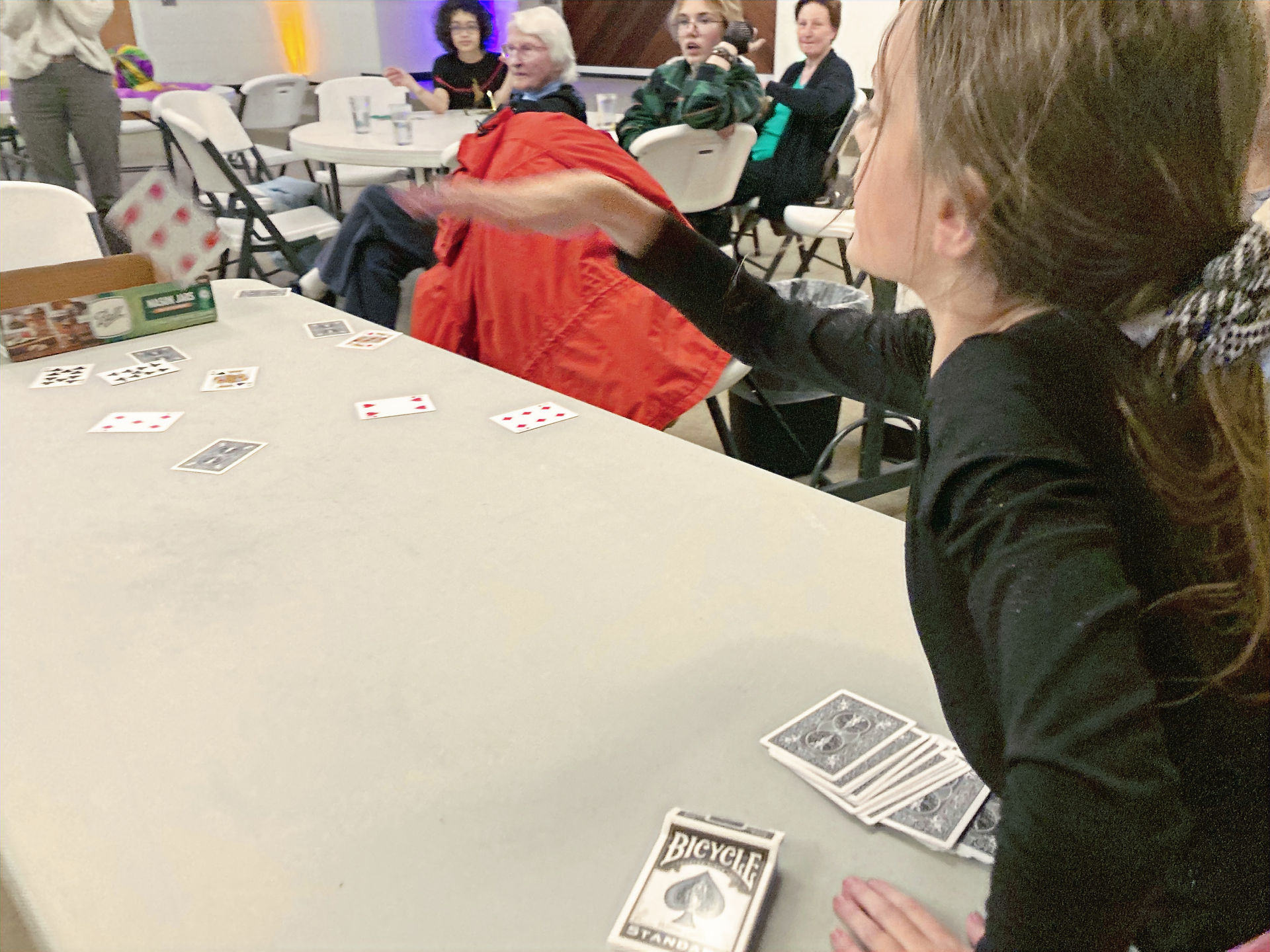 Parker leans in, trying to toss her playing cards in the box at the other end of the table.