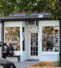Community bookstore storefront framed by leaves.