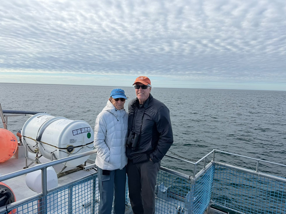 An older couple enjoys a peaceful moment on a boat deck, surrounded by the serene waters of the Bay of Fundy and a cloudy sky.