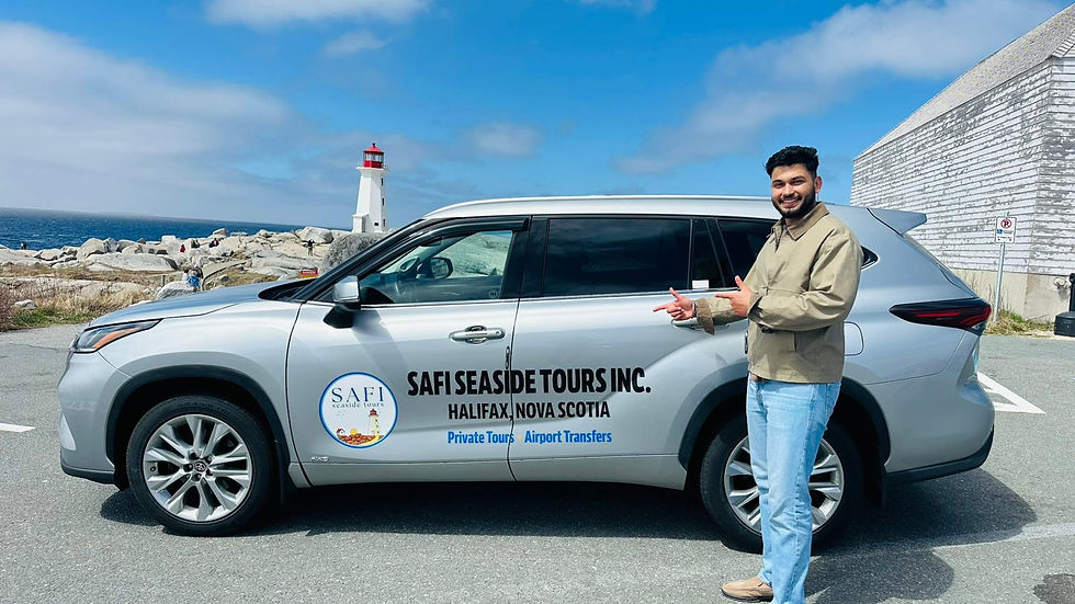 Smiling man points beside a silver Safi Seaside Tours SUV near a lighthouse on a rocky coast.
