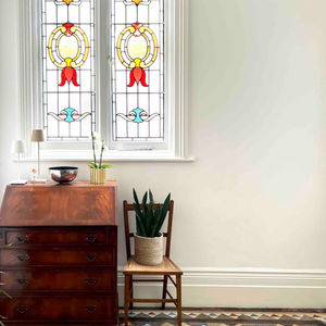vintage bureau and antique chair stand proudly in front of an original stained glass window, all complimented by original Minton floor tiles