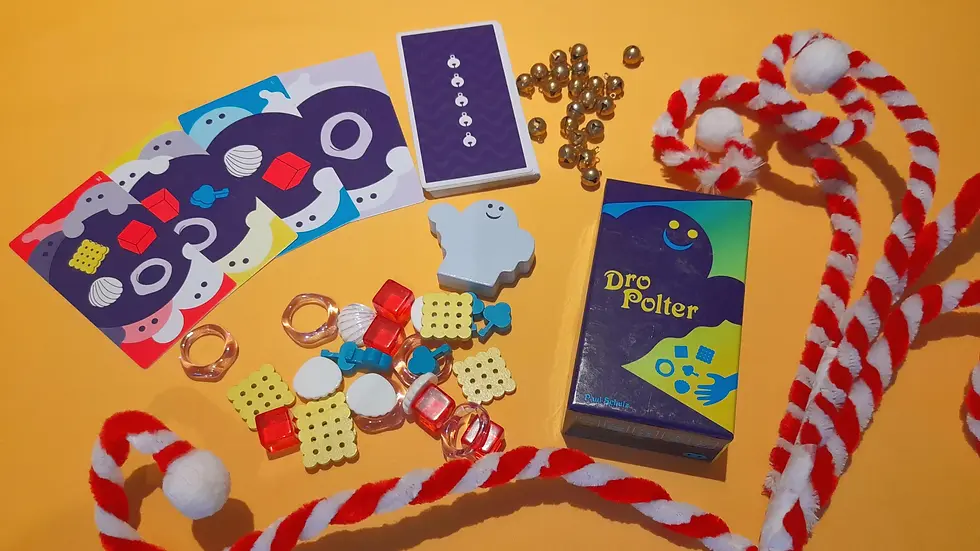 Colorful board game setup on orange background with cards, beads, ghost piece, and box labeled "Dro Polter." Red and white striped rope.