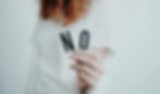 Person holding letters "NO" on cards against a white background, wearing a white shirt. Focus on hand; conveys a firm message.