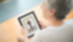 Elderly woman holds a framed photo of a man, set against a wooden floor. The scene is calm and nostalgic.