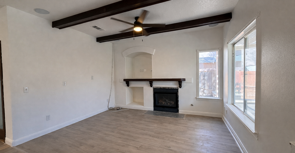 Family room with fireplace, exposed ceiling beams, and large windows