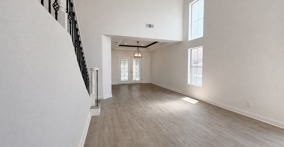 Bright living space with large windows and open layout connecting to dining area