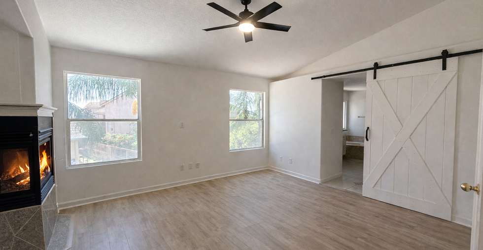 Spacious primary suite featuring a cozy fireplace and stylish barn door leading to the ensuite bath.