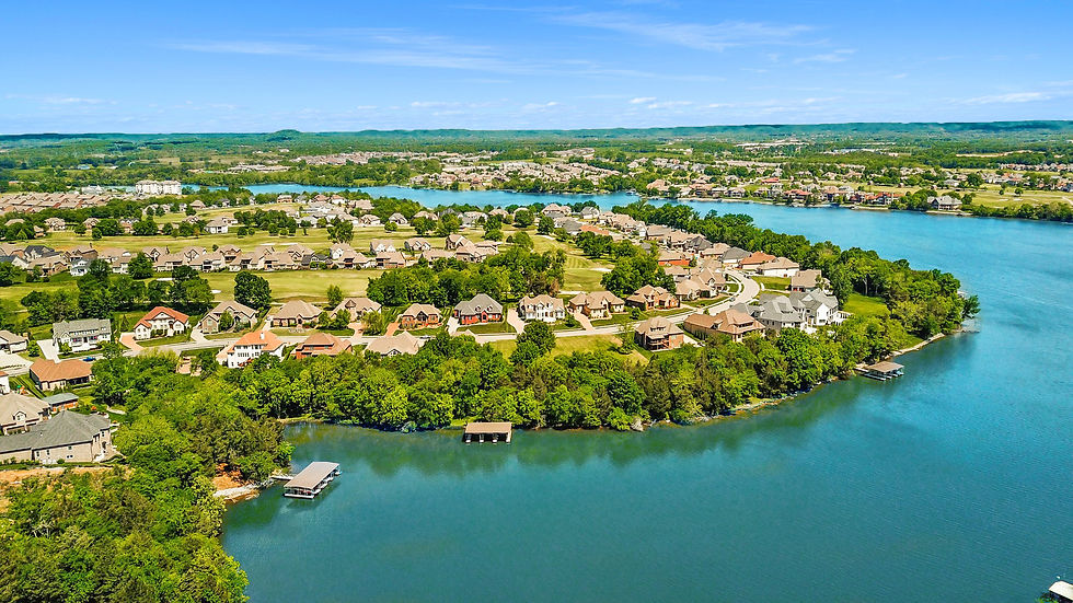 Old Hickory Lake Homes. Aerial view of a lakeside suburban neighborhood with rows of houses, green trees, docks, and bright blue water under a clear sky.