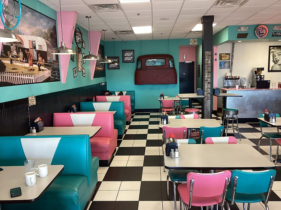 Better Days Dinner. Empty retro diner with turquoise and pink booths, black-and-white checkered floor, chrome counter, and wall art/old license plates.