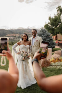 a photo of the bride and groom behind other people takng photos with their phone
