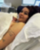 A woman cradling a new born baby in her arms and smiling at the camera