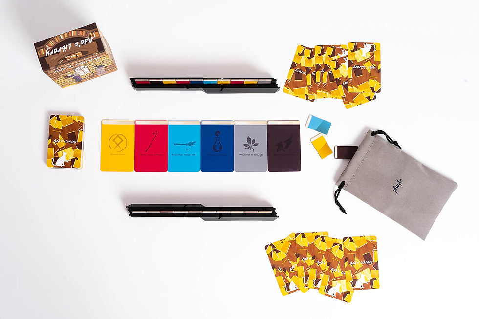 A board game setup of Ada's Library. A box, cards, a bad, a deck of cards, several scattered cards by the bag, and two opposing Game Racks with cards.