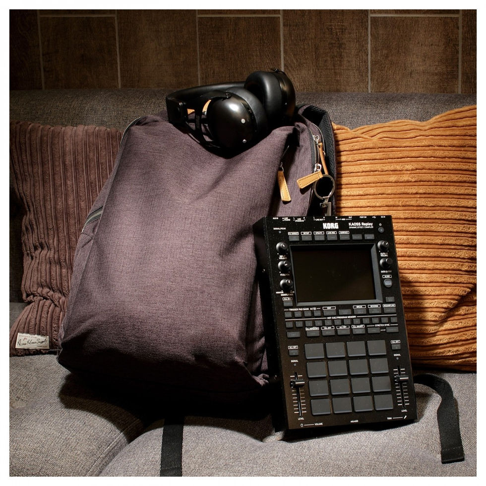 Image of Korg KAOSS Replay leaning against a grey backpack with headphones