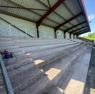 Bare concrete terrace at Trillick GFC after old seats were removed, ready for new seating installation.