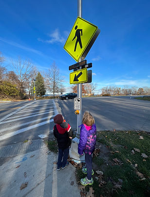 Two small kids look up at a pedesterian sign