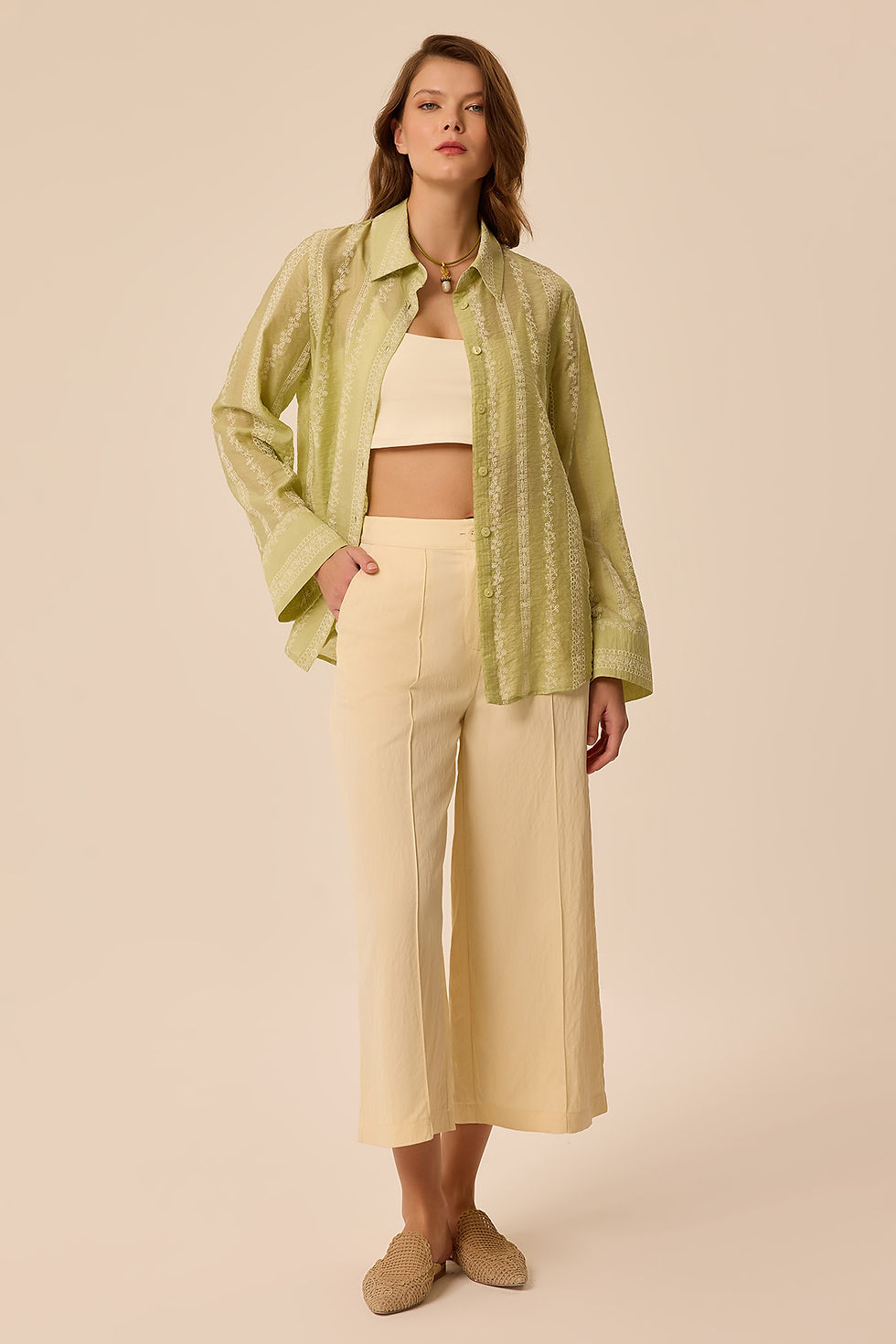 Model açık yeşil çizgili gömlek, krem crop top, açık sarı pantolon giyiyor.