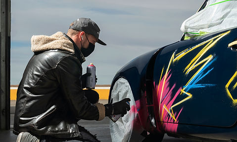 Color Cartel artist painting a vibrant graffiti design on a race car, showcasing unique automotive art customization