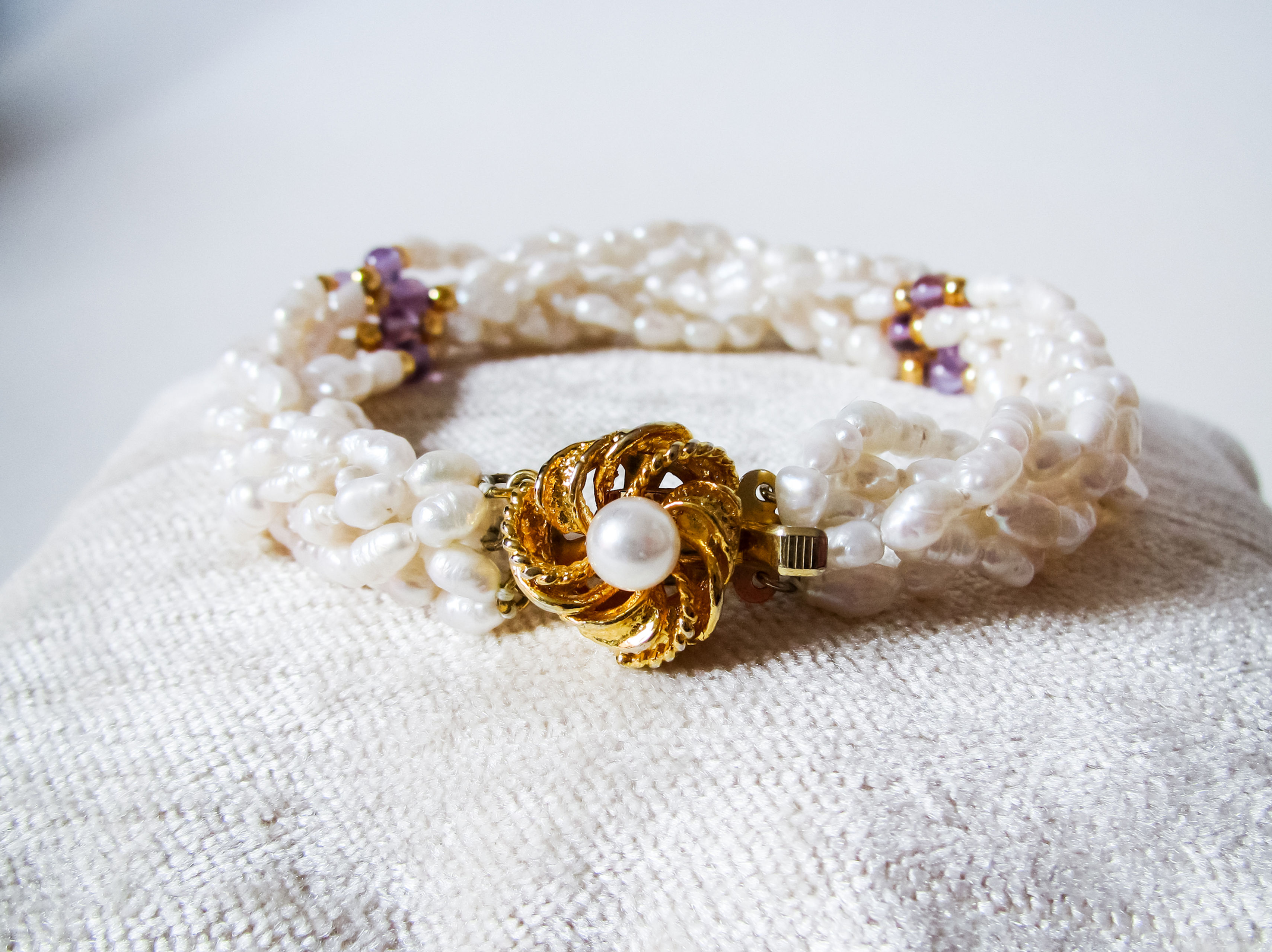 freshwater pearl twisted strand bracelet with amethyst and gold beads accents with an ornate push close clasp