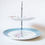 Thumbnail: two tier cake stand decorated with stylised roses and teal blue and white polka dots
