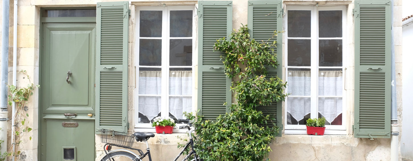 A bicycle in front of a house with green shutters, typical of the Île de Ré