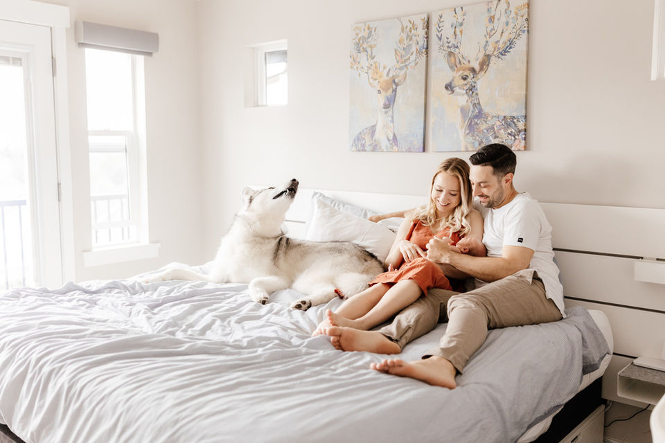 Meliza Orellana Photography_Home Page Gallery_Vancouver Maternity Photographer_Couple and pet lying on the bed admiring their newborn baby in their arms