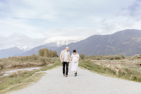 Meliza Orellana Photography_Home Page Gallery_Vancouver Maternity Photographer_Couple walking on a road, happy about the pregnancy and looking at the belly with the baby