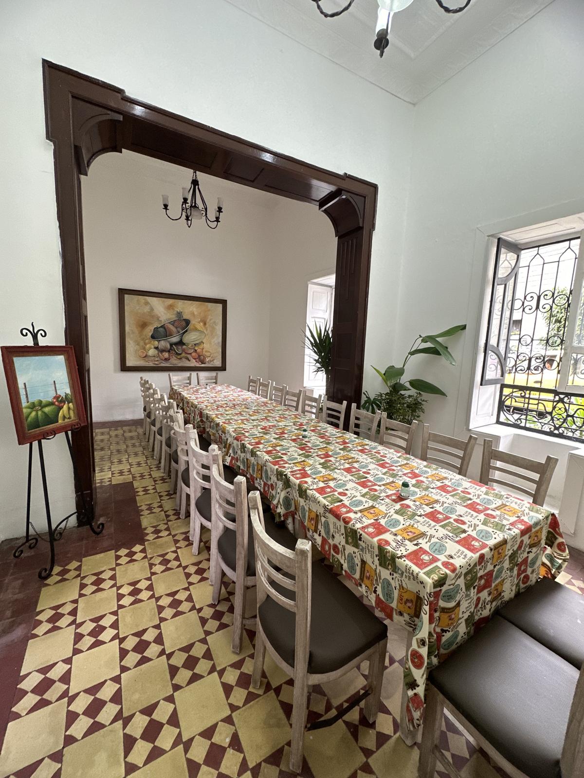 Salones conectados con mesas y sillas de madera en L’Antigua