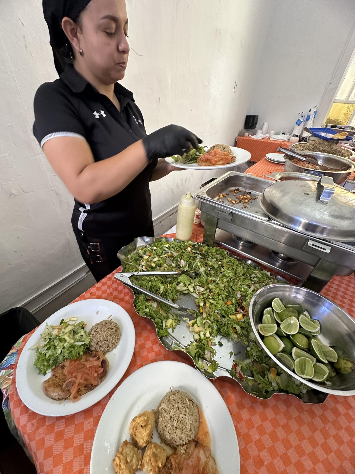 Personal de L’Antigua sirviendo almuerzos junto a las preparaciones del día