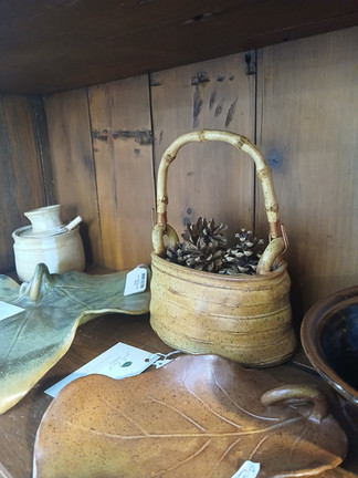 Garden-inspired ceramic pieces including leaf-shaped dishes and a small handled basket filled with p