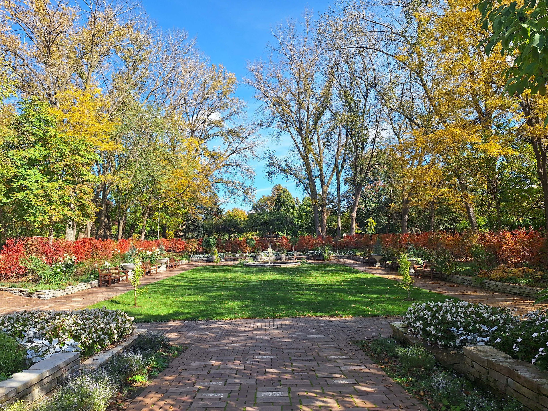 Bright fall colors in a sunken garden with a fountain in the center far away