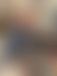 Artist seated at a pottery wheel shaping a clay vessel in a studio, smiling while working with clay.