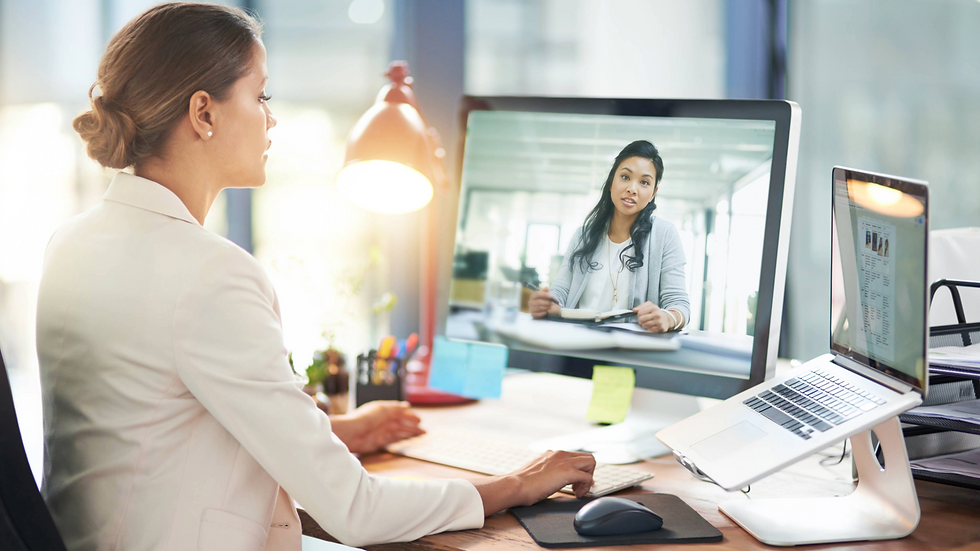 Woman at desk on a video meeting with a colleague, reviewing notes and metrics as part of a sales coaching session.