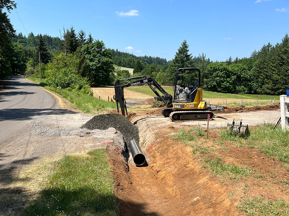 Excavator placing culvert pipe in rural residential driveway