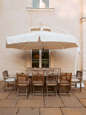 The castle patio with large outdoor dining table and open large cream parasol