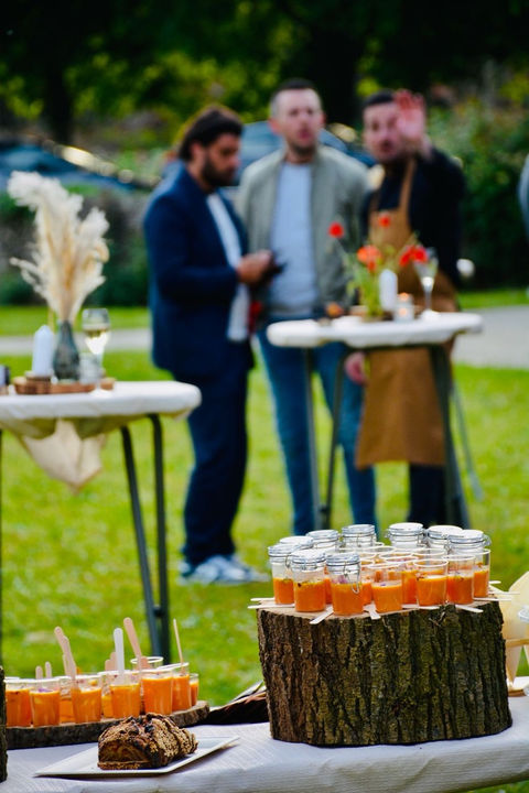 Gourmet appetizers in glass jars on wood stump displays during an outdoor event at Château Chevreuil