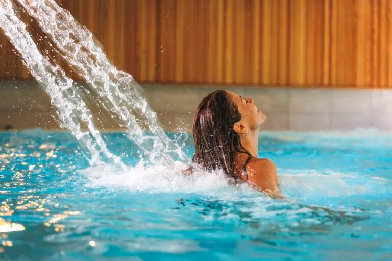 Femme profitant d’un jet d’eau massant dans une piscine intérieure