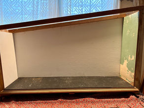 A small wooden structure with a black floor, white walls, and a shed roof.