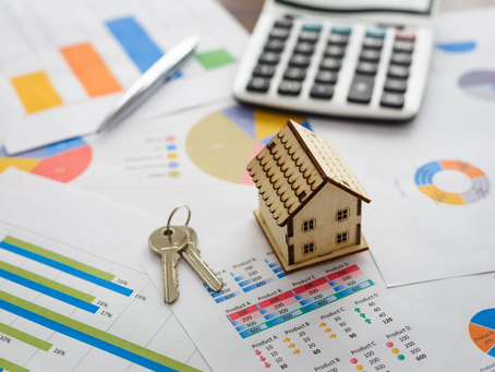 house keys and a wooden house model with financial statements on housing market