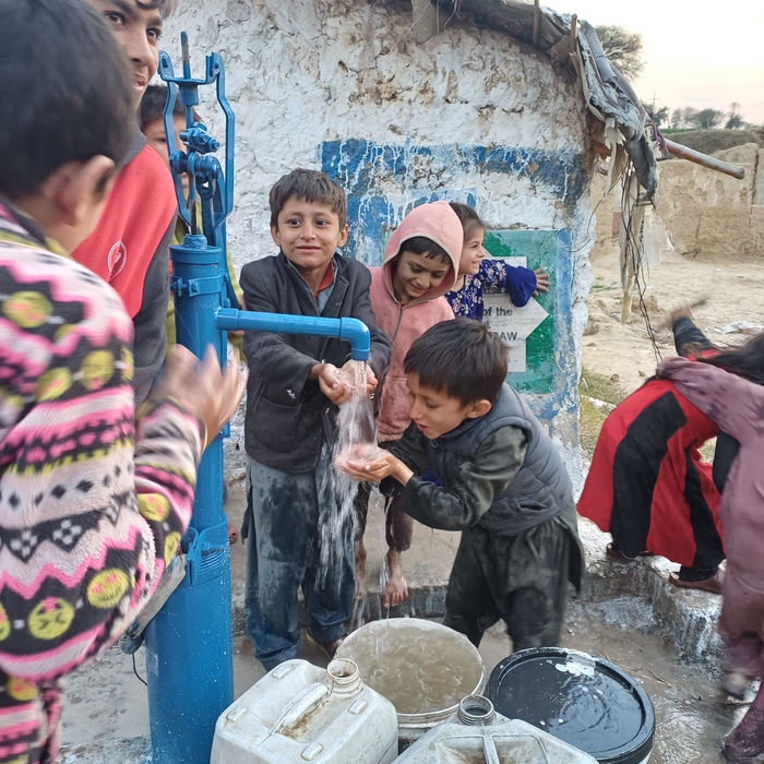 Kinder füllen Kanister an einer Wasserpumpe