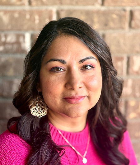 Woman with long dark hair in a pink sweater, smiling.