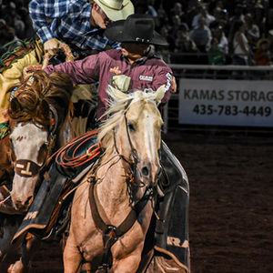 two men riding horses in front of a kamas storage sign